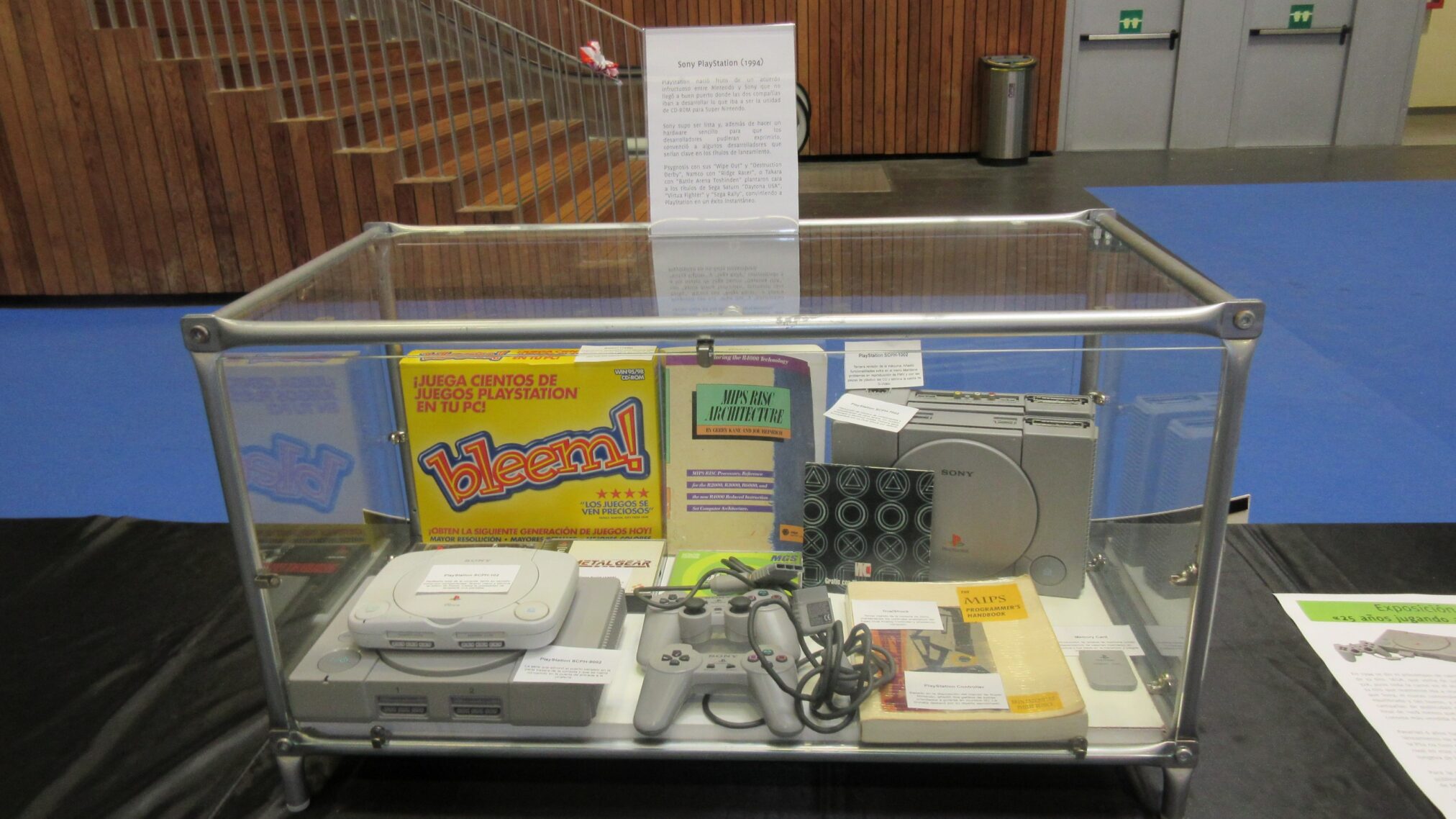 La consola PS1 expuesta en una vitrina junto con los mandos y algunos juegos La consola PS1 expuesta en una vitrina junto con los mandos y algunos juegos